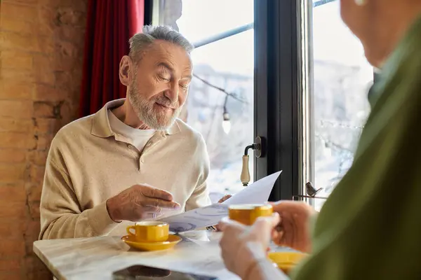A middle aged man and woman enjoy a delightful dinner date, sharing smiles over coffee. — Stock Photo