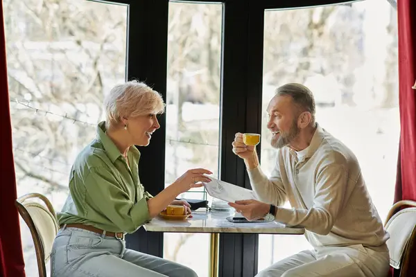 A joyful couple enjoys conversation and coffee in a warm, inviting cafe atmosphere. — Stock Photo