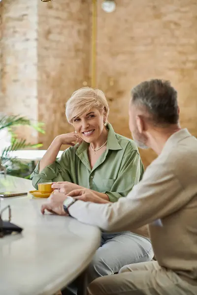 A middle-aged couple shares a joyful conversation over coffee in a charming cafe. — Stock Photo