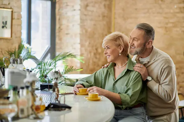 A mature couple shares laughter and smiles while savoring coffee together at a trendy cafe. — Stock Photo