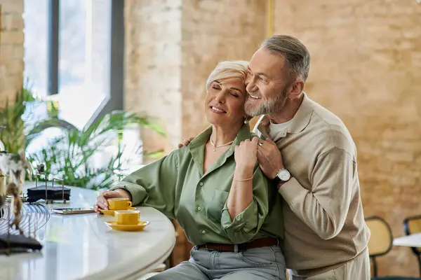 Um casal de meia-idade compartilha um momento quente enquanto toma café em um café acolhedor. — Fotografia de Stock