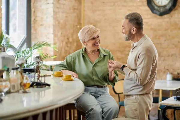 Two mature individuals share laughter and conversation while enjoying coffee at a charming cafe. — Stock Photo