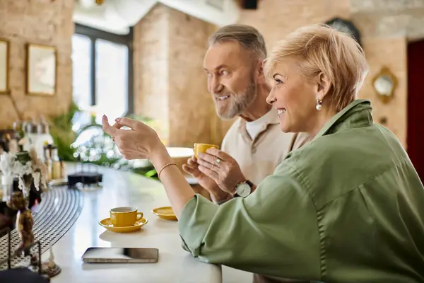 Ein älteres Paar lacht bei einem Kaffee in einem warmen, einladenden Café und genießt sein romantisches Date. — Stockfoto