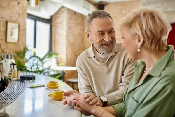 A middle aged couple shares a tender moment at a charming cafe, embracing romance and conversation. — Stock Photo