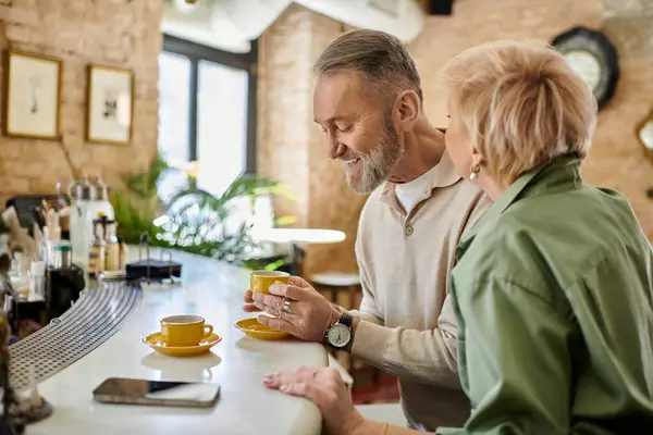 A middle aged couple shares a warm moment over coffee in a charming cafe setting. — Stock Photo