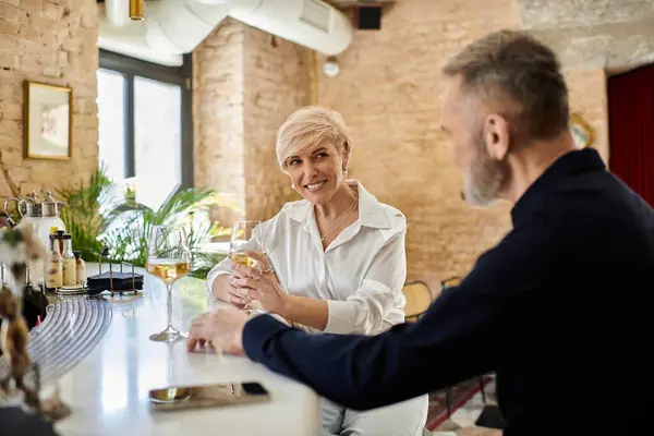 A middle aged man and woman share laughter and conversation while sipping wine in a cozy bar. — Stock Photo