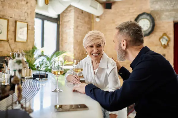 Middle aged man and woman share laughter and drinks in a warm, inviting setting during their date. — Stock Photo