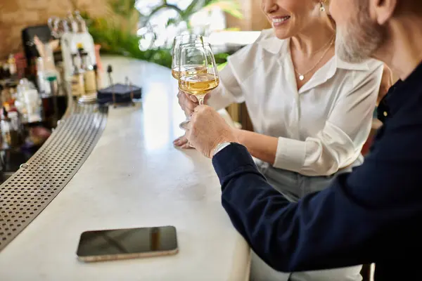 Mature couple shares a warm moment at a stylish bar while savoring drinks together. — Stock Photo