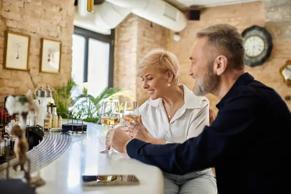 Middle aged couple shares an intimate moment at an elegant bar, laughter and drinks in hand. — Stock Photo