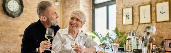 A middle-aged man and woman share laughter and wine during a romantic dinner together, banner — Stock Photo