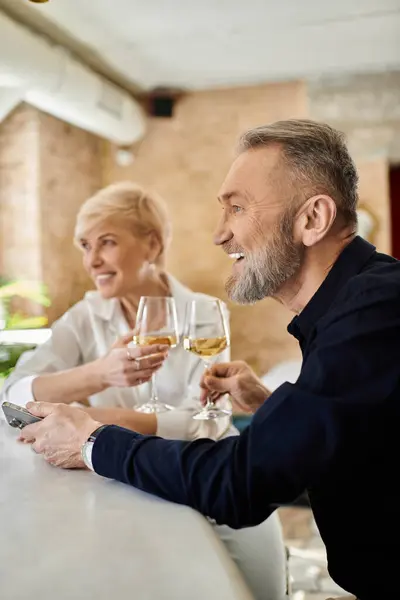 A middle-aged couple shares drinks and smiles at a cozy bar. — Stock Photo