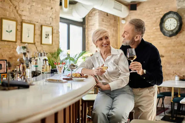 Zwei Personen mittleren Alters genießen Gesellschaft, schlürfen Wein und lächeln herzlich. — Stockfoto