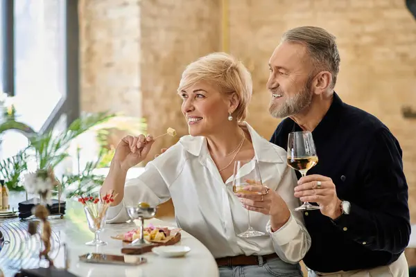 A middle aged couple shares laughter and drinks while savoring a delightful meal. — Stock Photo