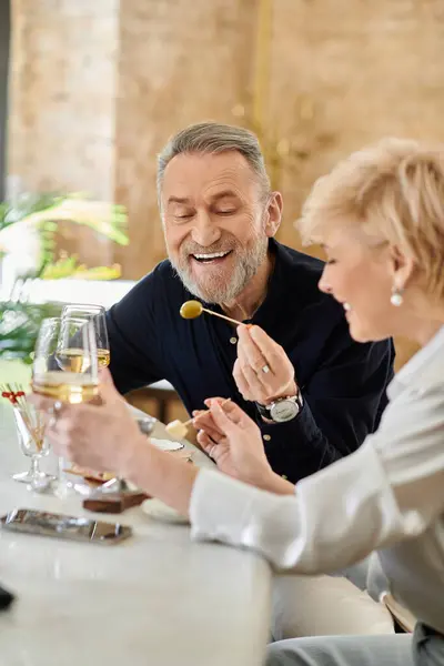 A joyful couple shares delicious drinks and appetizers while laughing together. — Stock Photo