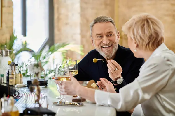 Middle aged couple enjoys an intimate evening, sharing laughter and drinks at a charming cafe. — Stock Photo