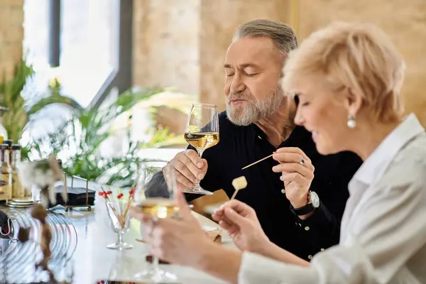 A mature couple savors their meal together, sharing joy and laughter over a lovely dinner setting. — Stock Photo