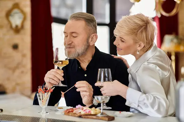 Middle aged couple shares an intimate moment over drinks and appetizers in a cozy setting. — Stock Photo