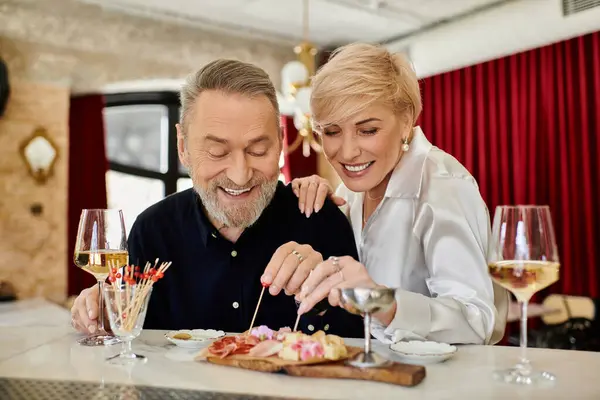 A middle-aged couple enjoys a lovely evening at a cozy cafe with gourmet meals. — Stock Photo