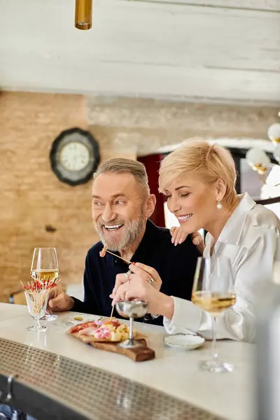 A middle-aged couple shares smiles and a delightful meal at a cozy eatery. — Stock Photo
