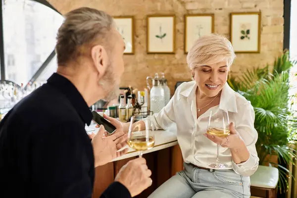 A beautiful mature couple shares laughter and drinks at a charming bar, basking in romance. — Stock Photo