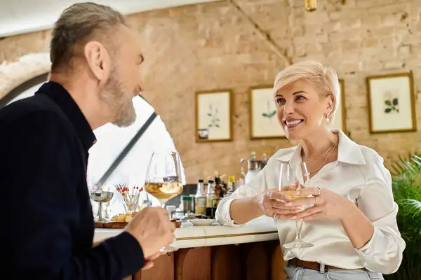 A middle-aged man and woman share drinks and laughter at a charming bar during a romantic date. — Stock Photo