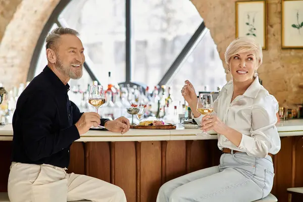 A delightful evening unfolds as a middle aged couple enjoys wine and conversation at a stylish bar. — Stock Photo