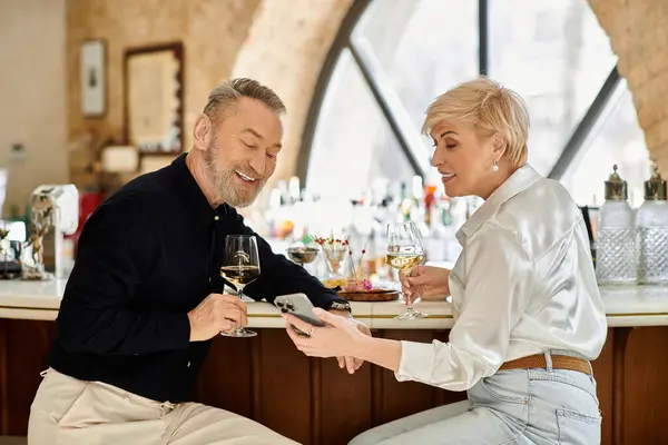 A middle-aged couple shares a joyful moment over drinks in a charming bar setting. — Stock Photo