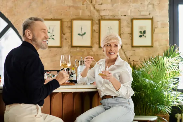 A middle aged couple enjoys warm moments together at a stylish bar while sipping wine. — Stock Photo