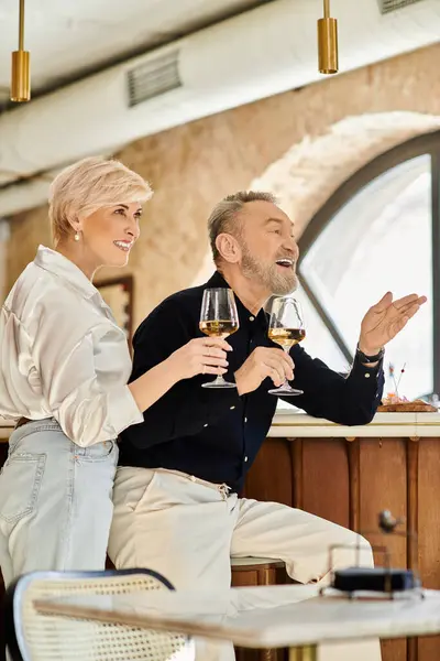A middle aged couple enjoys each others company while sharing glasses of wine at a romantic bar. — Stock Photo