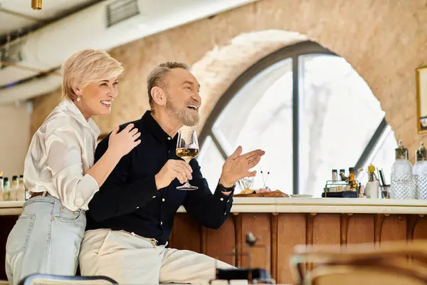 A middle aged couple shares a joyful moment over drinks at a cozy restaurant, embracing romance. — Stock Photo
