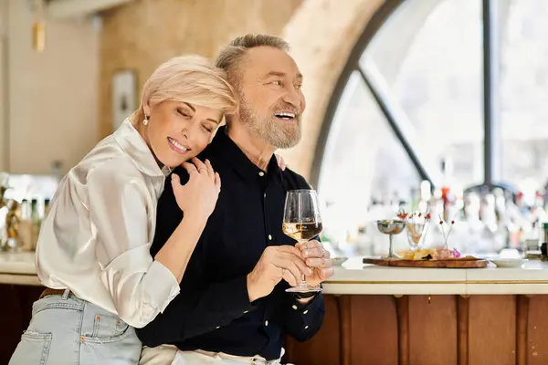 Ein Paar mittleren Alters teilt Lachen und Wärme an einer gemütlichen Bar und genießt zusammen feine Drinks. — Stockfoto