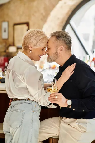A mature couple shares a romantic moment, hugging and enjoying drinks during a special date. — Stock Photo