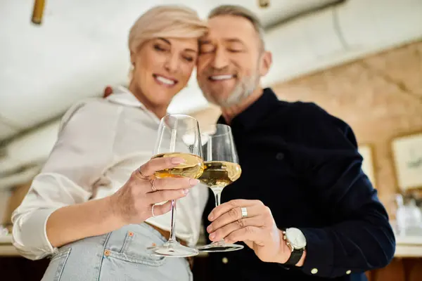 Zwei reife Menschen stoßen mit Wein an und feiern ihre Verbundenheit in einem gemütlichen Rahmen. — Stockfoto