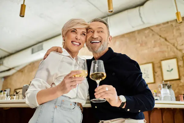 Ein Paar mittleren Alters genießt Cocktails und teilt fröhliche Momente in einer lebhaften Bar. — Stockfoto