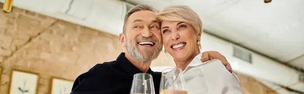 Mature couple smiles joyfully while clinking glasses in a cozy bar, banner — Stock Photo