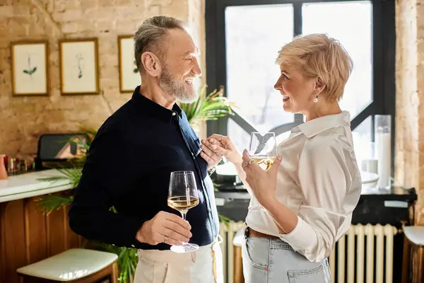 Ein Paar mittleren Alters lächelt fröhlich, während es in einer einladenden Bar Weingläser hält. — Stockfoto