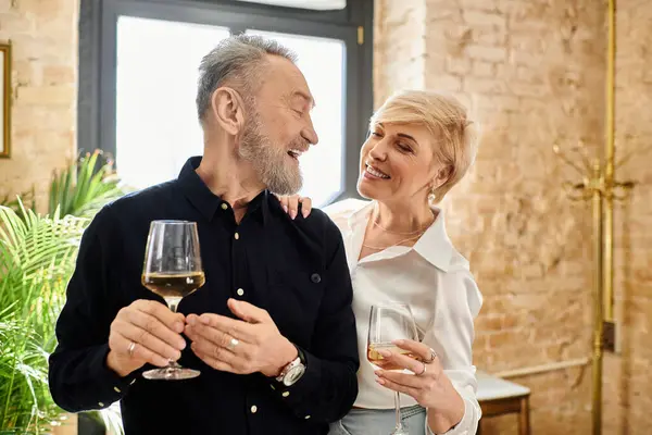 Ein Paar mittleren Alters lacht und genießt intime Momente bei Drinks in gemütlicher Atmosphäre. — Stockfoto