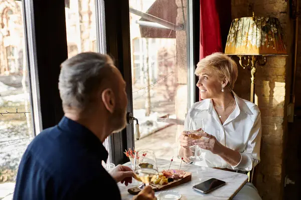 Mature couple shares laughter and wine while admiring the view during their romantic date. — Stock Photo