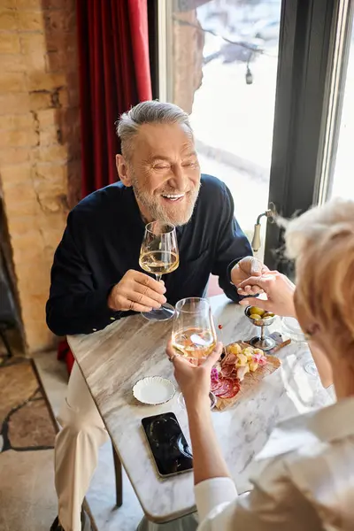 Um casal de meia-idade compartilha um momento alegre ao jantar, desfrutando de bom vinho e conversa. — Fotografia de Stock