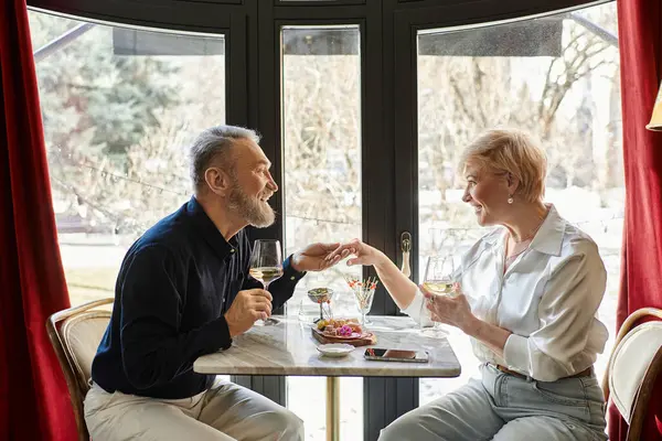 A middle aged couple enjoys a romantic dinner together, sharing tender moments. — Stock Photo