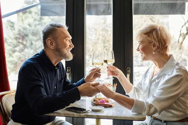 Casal de meia-idade compartilha momentos íntimos sobre copos de vinho, enquanto sentado em um café encantador. — Fotografia de Stock