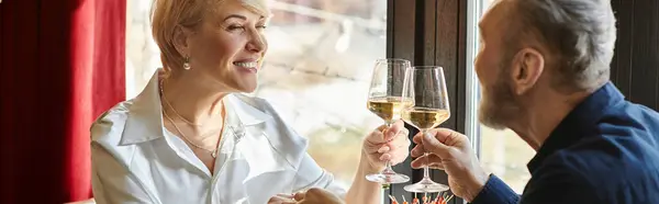 A middle aged man and woman share a special moment over drinks, smiling and toasting, banner — Stock Photo