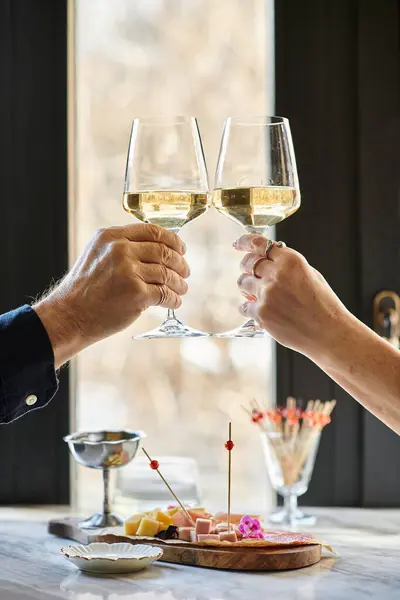 A middle-aged couple toasts with wine and appetizers, celebrating their love. — Stock Photo