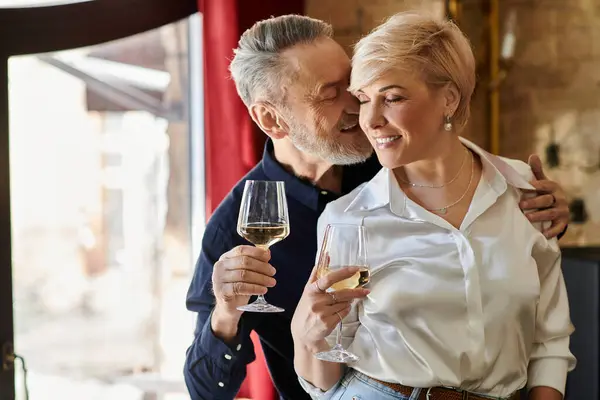 Um homem e uma mulher de meia-idade desfrutam uns dos outros da companhia enquanto bebem vinho em um espaço acolhedor e convidativo. — Fotografia de Stock