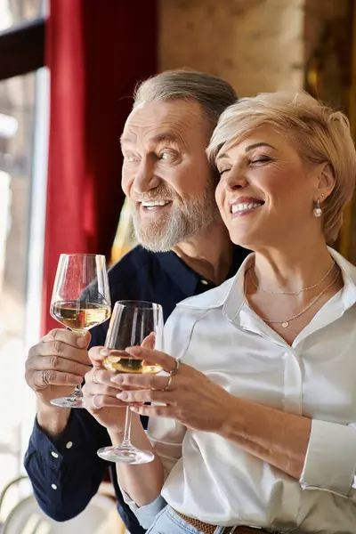 A charming couple clinks their glasses together, sharing joyful laughter and love. — Stock Photo