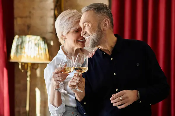 Um homem e uma mulher de meia-idade compartilham um momento alegre, batendo os óculos em comemoração. — Fotografia de Stock