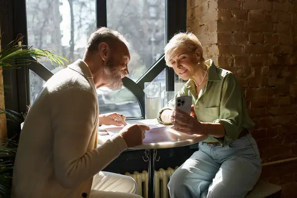 A middle aged couple enjoys each others company while looking at a mobile phone together. — Stock Photo