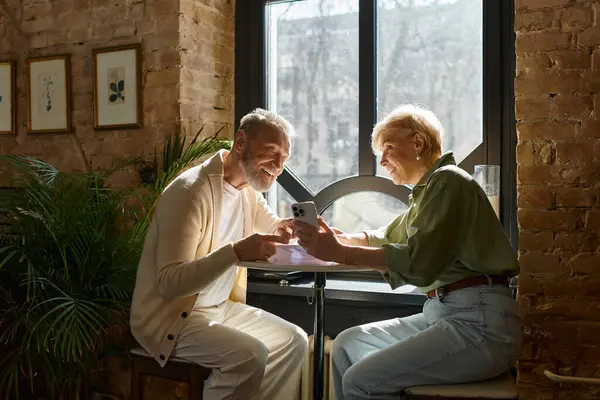 A middle-aged couple shares laughter while enjoying a cozy moment in a charming cafe. — Stock Photo