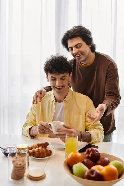 Gay couple shares a special moment in their stylish apartment, enjoying breakfast and laughter. — Stock Photo