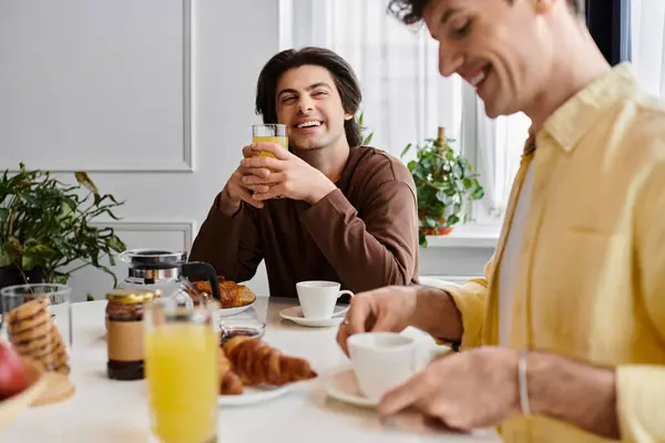 Gay couple shares a joyful breakfast in their modern apartment, celebrating their love and connection. — Stock Photo